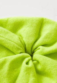 Heldere neon groene gebreide stof, met een zachte textuur en ronde beweging; glad, rekbaar, met nauwkeurige stiknaden en geen zichtbare patronen.