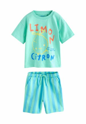 T-shirt verde chiaro con una grafica di limone e testo, abbinata a pantaloni corti a righe blu. Entrambi gli articoli sono realizzati in morbido cotone.
