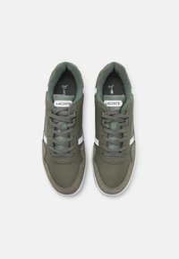 Žalios odinės sportbačiai su pilkais zomšiniais akcentais, baltais dryžiais ir pilkomis raišteliais. Turime paminkštintą apykaklę ir prekės ženklo etiketę ant liežuvėlio.