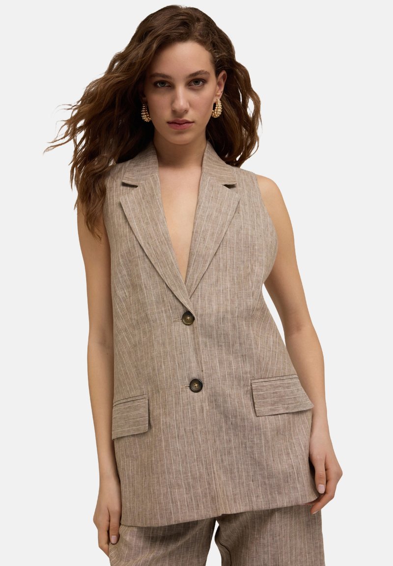 Beige Leinenweste mit einem Reverskragen, vertikalen Streifen, Fronttaschen und zwei Knöpfen. Sanfte Textur, maßgeschneiderter Schnitt.