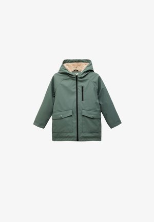 Veste extérieure verte avec une doublure beige duveteuse, fermeture éclair au devant, deux grandes poches et une capuche. Le matériau semble lisse avec une finition mate.