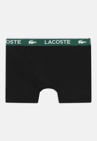 Sorte boxer shorts med en grøn og hvid elastisk talje med "LACOSTE" logoet og et krokodille emblem. Glat bomuldsstof.