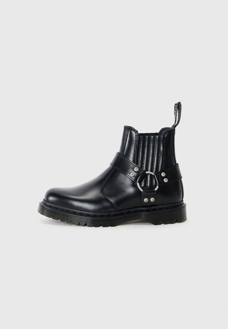 Zwarte leren enkelboots met ribbelachtige elastische zijkanten, een metalen gespaccent en een gestructureerde zool voor grip.
