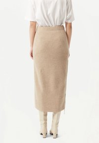 Stickad midikjol i beige, med en texturerad ribbad design och elastisk midja. Avslutad med en sidodragskedja.