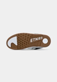 Σόλα παπουτσιού με καφέ ελαστική τριβή, λευκές επιφάνειες πρόσφυσης, κυκλική λεπτομέρεια και λογότυπο "ETNIES" σε λευκό στο κέντρο κάτω.