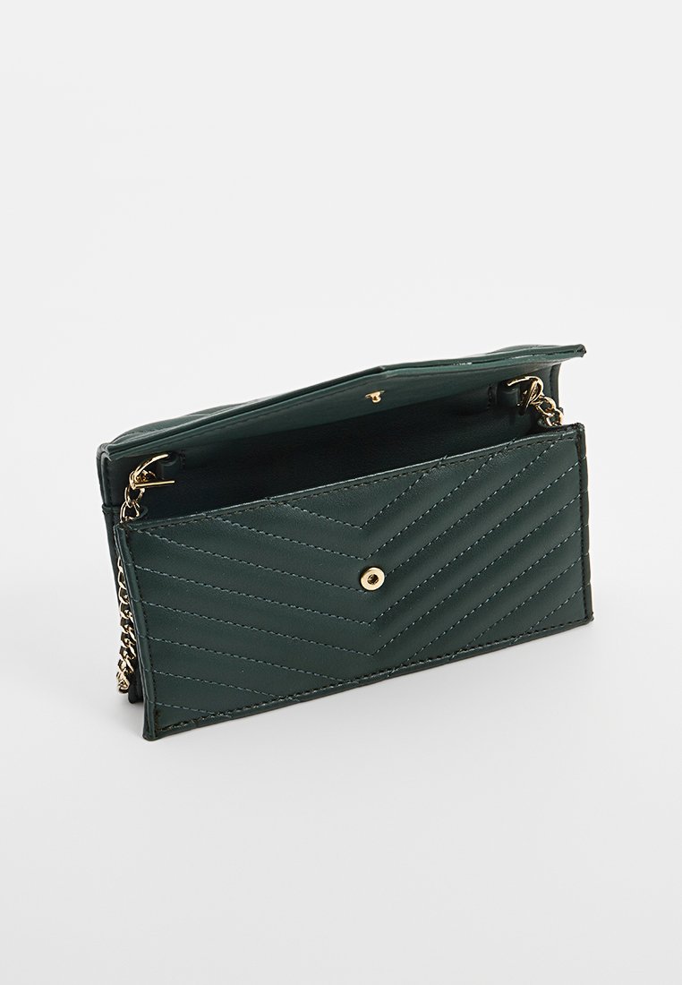 Portefeuille en cuir matelassé vert avec fermeture à bouton pression doré et une chaîne. L'intérieur comporte un compartiment unique avec une doublure contrastante.