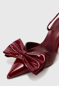Escarpin slingback brillant bordeaux à bout pointu avec un grand nœud décoratif à l'avant.
