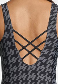 Maillot de bain noir avec un motif géométrique gris, doté d'un dos plongeant et de bretelles croisées pour un soutien amélioré et un détail de design.