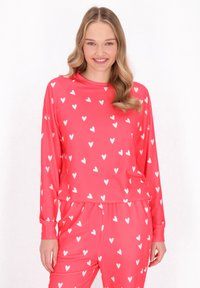 Roze pyjama set met een langemouwen shirt en een losse broek met een wit hartpatroon. Gladde, lichte stof. Elastische tailleband.