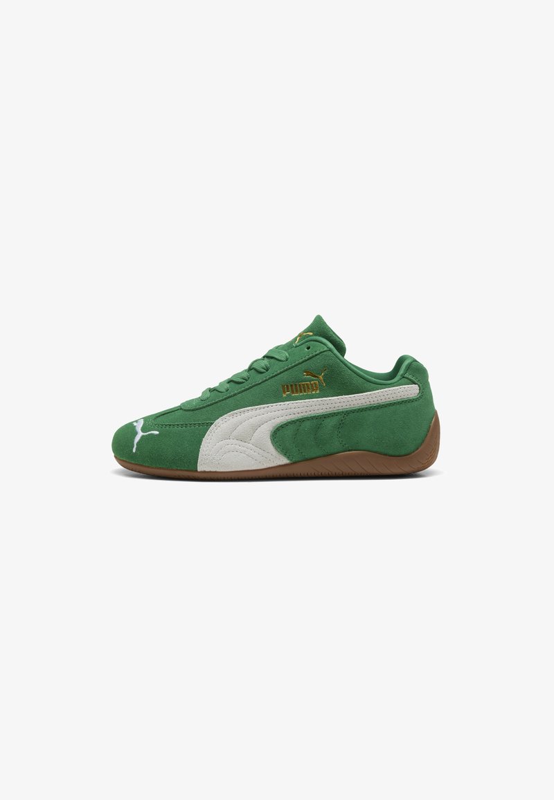 Baskets Puma en daim vert avec une bande blanche, logo Puma doré et semelle marron, vues de profil sur fond blanc.