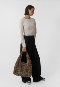 Beige pikatamütsiga crop-top, mustad laiad püksid ja pruun leopardimustriga kott. Tekstuuriga materjal koos kumerate käepidemetega. Igapäevased jalatsid.