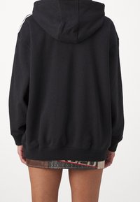 Sudadera negra con capucha, de mangas largas, puños acanalados y cordón. Presenta un corte ligeramente holgado y un acabado texturizado.