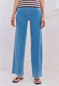 Pantaloni in denim azzurro chiaro a gamba larga con vita alta, caratterizzati da un classico design a cinque tasche e dettagli di cuciture sottili.