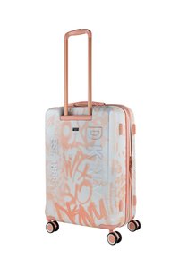 Maleta rígida blanca con patrones coloridos tipo grafiti en tonos durazno y coral. Cuenta con un asa retráctil y ruedas multidireccionales.