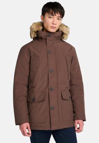 Brun parkajakett med pälsförsett huva, fyra framfickor, knäppning med knapp och en slät textur. Lämplig för kallt väder.