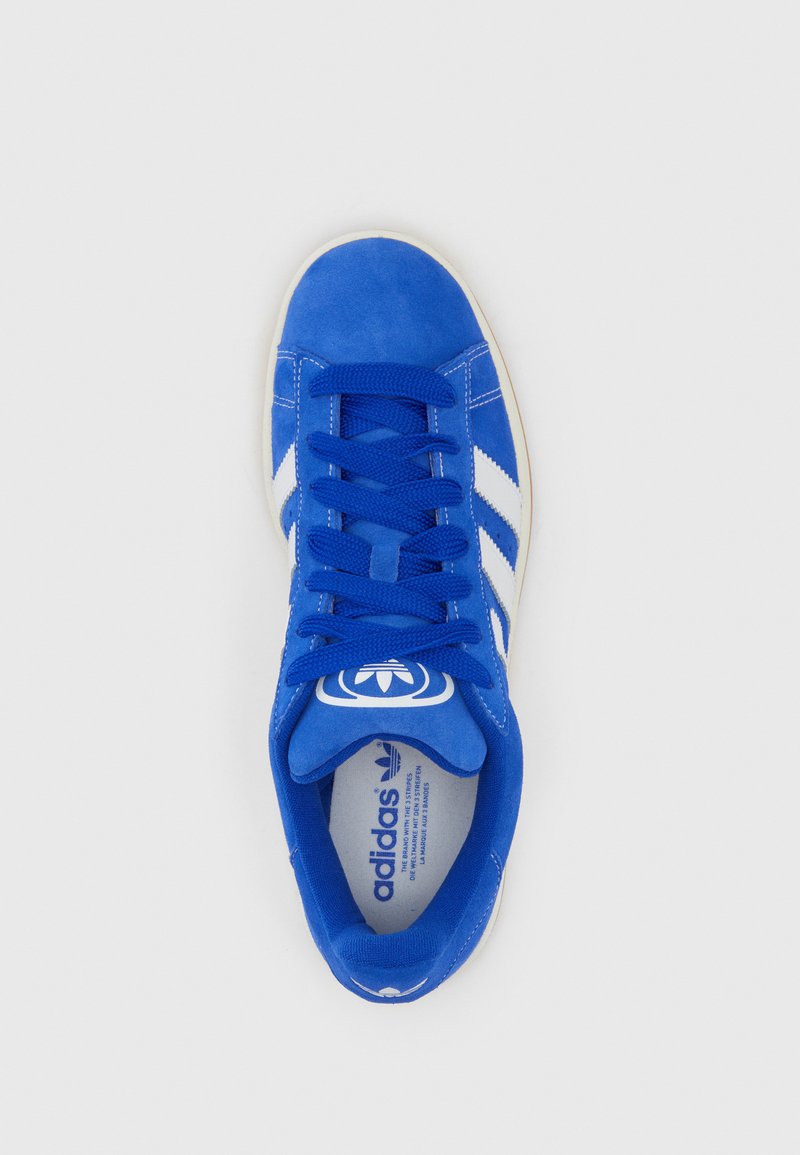 Blaues Wildledersportschuh mit weißen Streifen, runder Zehenpartie, flachen Schnürsenkeln und gepolsterter Zunge. Verfügt über ein Logo auf der Zunge und eine strukturierte Sohle.