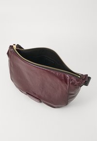 Borsa in pelle bordeaux con finitura liscia, chiusura con zip e interno nero. Dotata di tracolla removibile e design minimalista.