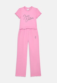 Różowy dwu-elementowy zestaw wypoczynkowy z krótkim rękawem z napisem "Juicy Couture" oraz spodniami o szerokich nogawkach z logo "JC" na lewej udzie.