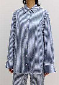 Blau-weiße gestreifte, oversized Bluse mit Knopfverschluss, spitzem Kragen und breiten Manschetten mit kontrastierenden Streifen. Weicher Stoff.