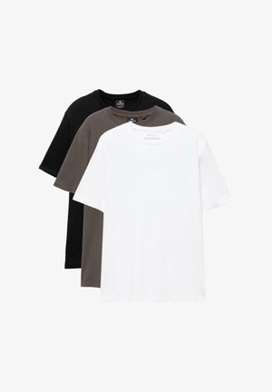 Trois t-shirts unis à col rond empilés l'un devant l'autre en blanc, gris foncé et noir sur un fond blanc.