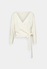 Vrchní díl z krémové pleteniny; má hluboký výstřih do V, dlouhé rukávy a detail se zavazováním na boku. Hladká texturá s žebrovanými manžetami.