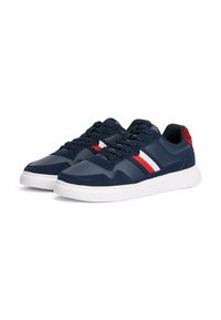 Sneaker navy con texture liscia, caratterizzate da strisce bianche e rosse, una suola in gomma bianca e un accento del tallone navy solido.