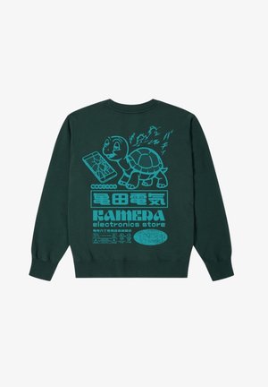 Felpa verde con grafica di una tartaruga, testo blu e illustrazione di un telefono rotto sulla schiena. Il tessuto sembra morbido; include polsini a costine.