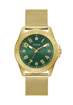 Montre-bracelet avec bracelet en maille dorée, cadran vert, chiffres et aiguilles dorés, accents en diamant, et logo "GUESS" au centre.
