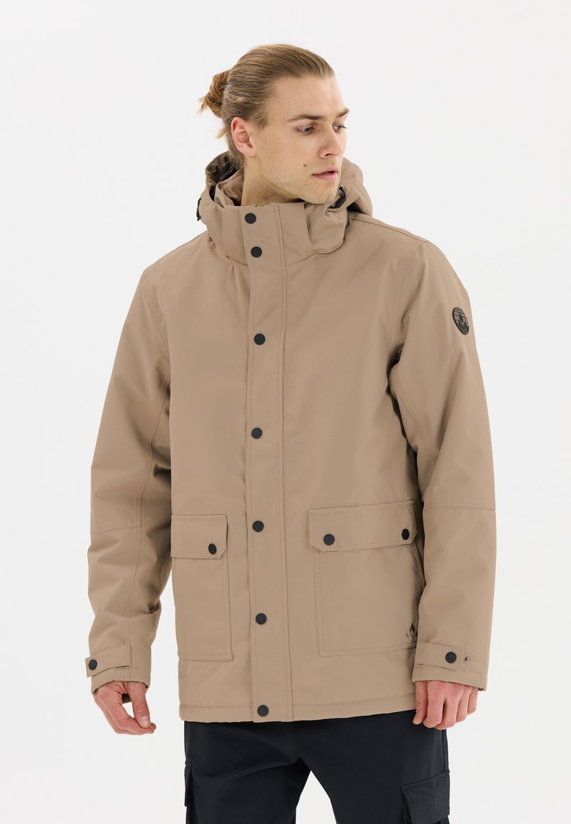 Beige vattentät jacka med huva, framsnapplås, två stora framfickor, justerbara ärmslut och sidoventilation. Svart logotypapplikation.
