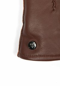 Braunes Lederprodukt mit strukturierter Oberfläche, versehen mit einem silbernen Knopf mit geprägten Initialen. Genähte Kantenverzierung am oberen Rand.