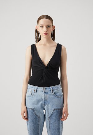 Black bodysuit with a deep V-neck and twisted front; paired with light blue high-waisted jeans featuring large front pockets and faded texture.