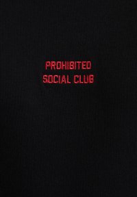 Schwarzer gerippter Stoff mit rotem besticktem Text "PROHIBITED SOCIAL CLUB", der zentriert auf dem Kleidungsstück platziert ist. Keine weiteren sichtbaren Muster oder Details.