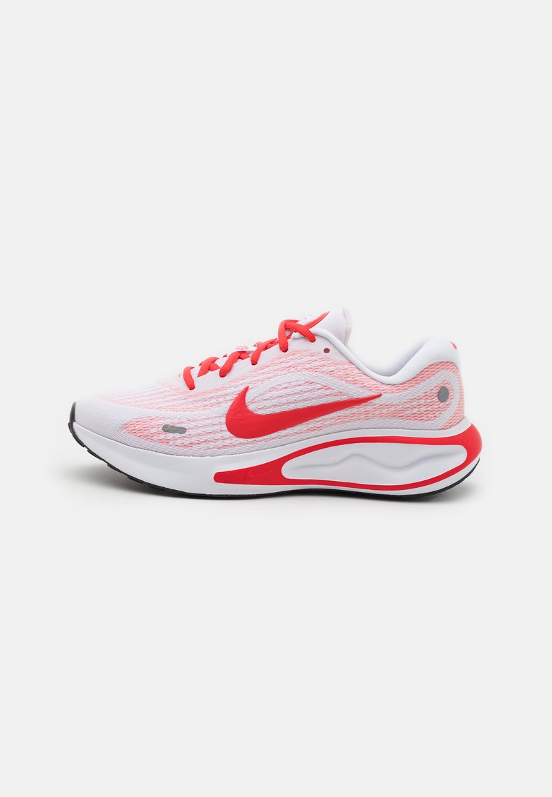Nike running shoes with a white mesh upper featuring red accents, reinforced toe, and thick sole with a unique wave pattern.