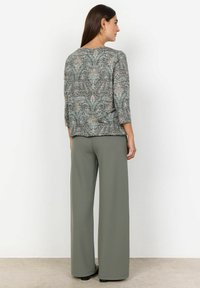 Haut à motifs multicolores avec un col rond et des manches trois-quarts, associé à un pantalon à taille haute à jambes larges de couleur olive.