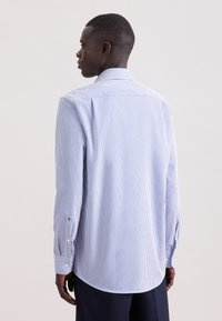 Camicia a righe blu e bianche, realizzata in tessuto leggero, con colletto classico, maniche lunghe con polsini abbottonati e orlo curvo.