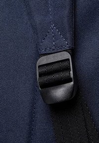 Correa de tejido navy con un regulador de plástico negro, que presenta dos secciones trenzadas y un detalle de costura triangular en el punto de sujeción.