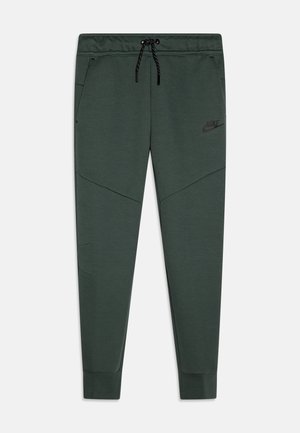 Ciemnozielone, zwężane spodnie dresowe z regulowanym czarnym sznurkiem w pasie, bocznymi kieszeniami, logo Nike na lewej udzie oraz ściągaczami przy kostkach.