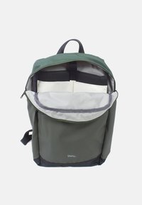 Grüner Rucksack mit schwarzem Boden, Reißverschlussöffnung und Netzfach. Das Innere umfasst Fächer zur Organisation und eine textile Oberfläche.