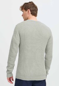 Lys grå strikkegenser med en teksturert ribbekantdesign, lange ermer og rund hals, med rett avslutning og tettsittende mansjetter.