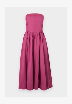 Φούξια αμάνικο φόρεμα με εφαρμοστή μπούστο, κάθετες ραφές και φουσκωτή φούστα που φτάνει μέχρι τη μέση της γάμπας σε μονόχρωμο φόντο.