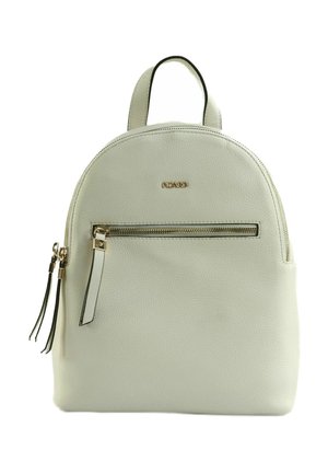 Sac à dos en cuir blanc avec poche zippée dorée, tirettes en cuir assorties et une poignée supérieure.