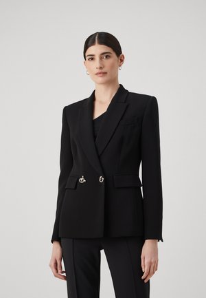 Blazer nero su misura in tessuto strutturato. Presenta un design doppiopetto, dettagli in hardware argentato e tasche laterali. Texture liscia.
