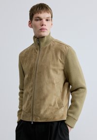 Taninribbonust sametjakk koos soonikkoelusega varrukate, kõrge krae, esikindluse ja küljetaskuga. Siidine tekstuur ja kaasaegne, struktureeritud lõige.