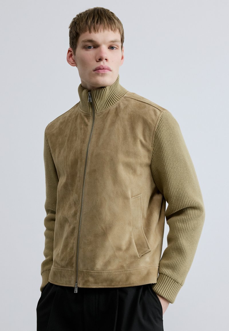 Taninribbonust sametjakk koos soonikkoelusega varrukate, kõrge krae, esikindluse ja küljetaskuga. Siidine tekstuur ja kaasaegne, struktureeritud lõige.