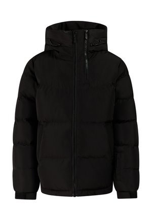 Meisje met een zwarte beanie en jas met sterretjesbroek en zwarte laarzen, staand met handen in de jaszakken.
