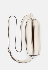 Krämfärgad läderaxelväska med dragkedjestängning, böjd form och en smal rem. Har kontrasterande mörka kanter och en slät textur.