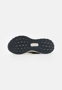 Trail running shoe sole, featuring a textured black rubber outsole with prominent traction patterns, white midsole, and a stable heel design.