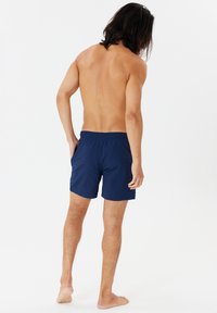 Mörkblå badshorts med elastisk midja, med en enda bakficka och en lätt, smidig tygtextur.