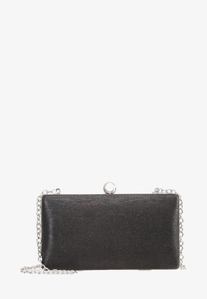 Pochette rectangulaire noire avec une bandoulière en chaîne argentée et un fermoir rond en argent sur le dessus, présentée sur un fond blanc.