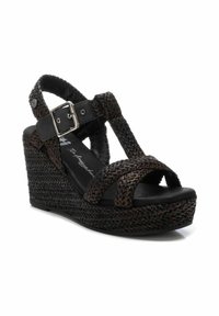 Sandalia cuña negra con tiras superiores trenzadas, hebilla ajustable y plataforma texturizada. Diseño de punta abierta con plantilla acolchada.
